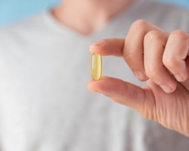 Pessoa segurando uma cápsula de vitamina D