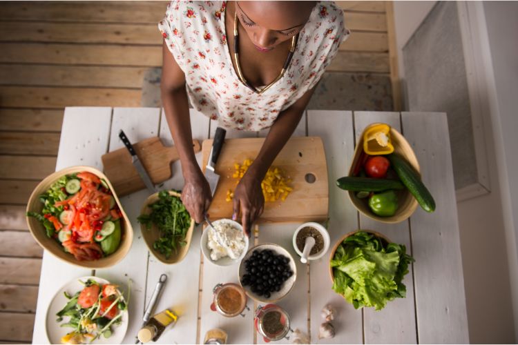 Mulher negra preparando mesa de comida saudável pensando em como fortalecer a imunidade
